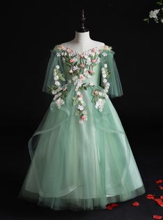 a green dress with flowers on it and petals scattered around the dress, which is part of a mannequin's torso