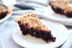 blueberry crumb pie on a white plate with another slice in the foreground