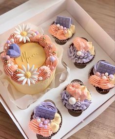 cupcakes decorated in pastel colors with flowers and ribbons are on a tray