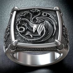 Show your allegiance to House Targaryen with our Targaryen House Dragon GOT Symbol Fan Art Signet, crafted from high-quality 925 sterling silver. This stunning ring features the iconic three-headed dragon sigil of House Targaryen, symbolizing power, strength, and a legacy of fire and blood. Perfect for fans of the epic fantasy series, this adjustable ring ensures a comfortable fit for any finger size. Handcrafted with meticulous attention to detail, the polished finish enhances the intricate des Dragon Rings For Men, Dragon Ring Mens, Armor Rings, Targaryen House, Large Dragon, Celtic Pendant, Viking Ring, Dragon Ring, Masonic Ring