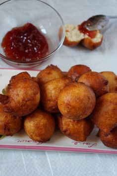 fried food on a plate with ketchup and bread in the bowl behind it