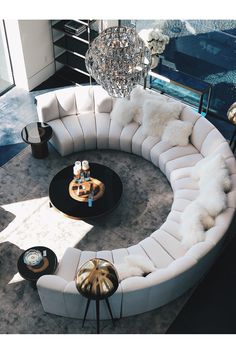 a living room filled with white furniture and a chandelier hanging from the ceiling