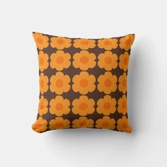 an orange and brown flower pattern pillow on a white wall with a black back ground