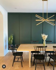 a dining room with green walls and wooden floors