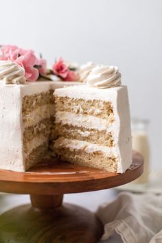 a cake with white frosting and pink flowers on top is cut in half to show the inside