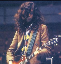 a man with long hair playing an electric guitar