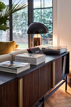 two books are sitting on top of a table in front of a couch with a lamp