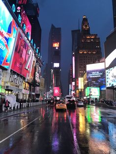 a city street at night with cars and billboards on the buildings in the rain