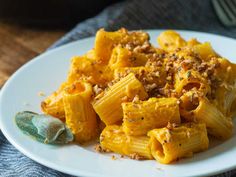 a white plate topped with pasta covered in sauce and seasoning next to a skillet