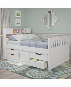 a white bed with two drawers underneath it and a mirror on the wall behind it