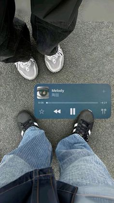 two people standing next to each other with their feet on the ground and one person holding an mp3 player