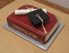 a cake made to look like a book with a graduation cap and tassel on top