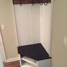 an entryway with a bench and coat rack on the wall, along with wooden flooring