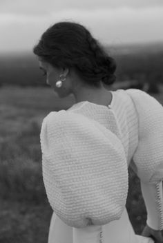 a woman in a white dress is walking through the field with her back to the camera