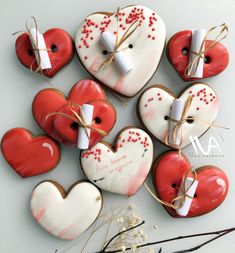 heart shaped cookies tied with twine and decorated with red and white icing are arranged on a table