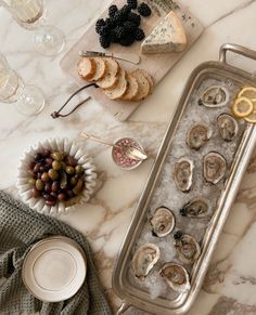 an assortment of food is displayed on a marble counter top with wine glasses and plates