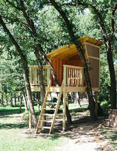 a wooden tree house in the middle of a park with stairs leading up to it