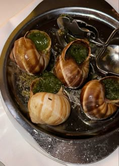 snails are being cooked in a pan with pesto