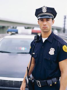 a police officer is standing in front of his patrol car and looking at the camera