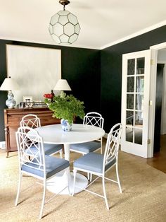 a white table with four chairs and a potted plant sitting on top of it