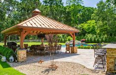 a gazebo sitting in the middle of a lush green yard next to a swimming pool