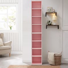 a living room with a pink book shelf next to a white chair and rug on the floor