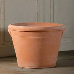 a large clay pot sitting on top of a hard wood floor next to a wall