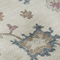 an area rug with various colored flowers and birds on the top, in front of a white background