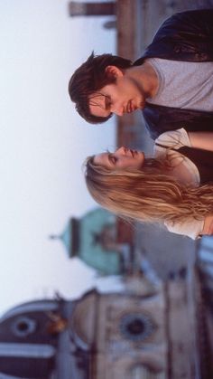 two people standing next to each other in front of a clock tower