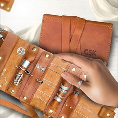 a person holding a brown leather belt with lots of rings and bracelets on it