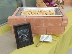 a table with some food on it and a sign next to it that says samosas