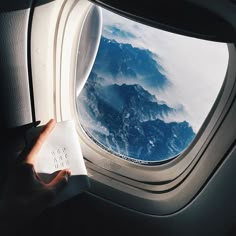 an airplane window with the view of mountains and clouds from it's seat area