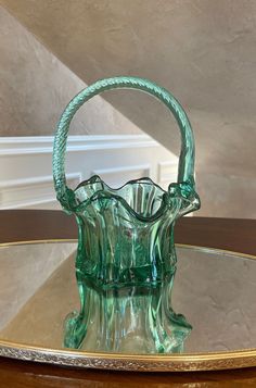 a green glass basket sitting on top of a wooden table