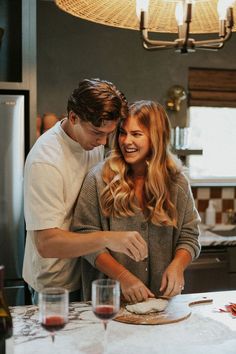 a man and woman standing in front of a counter preparing food