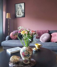 a living room filled with furniture and flowers on top of a coffee table in front of a window