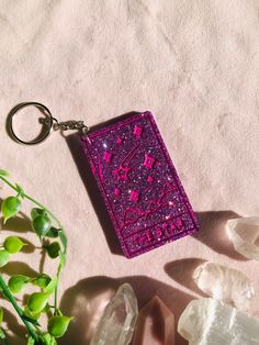 a pink keychain sitting on top of a table next to crystals and plants