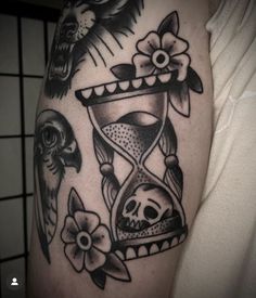 a tattoo with an hourglass and skulls on it