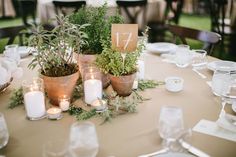 the table is set with candles and potted plants