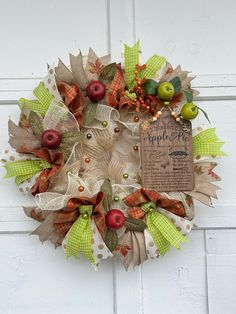 a wreath with apples and leaves hanging on a door