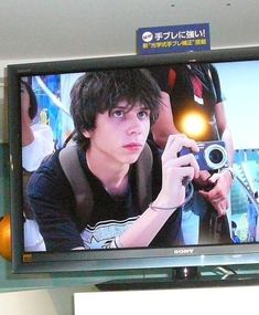 a man holding a camera in front of a flat screen tv