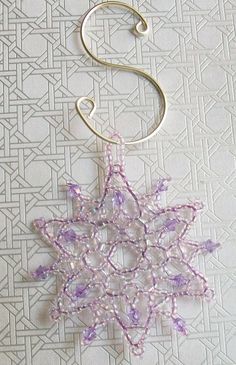 a snowflake ornament hanging from a hook on a white wallpaper