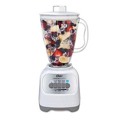 a blender filled with lots of fruit on top of a white counter