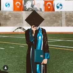 a person wearing a graduation gown and holding a cell phone to their ear while standing on a field