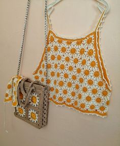 an orange and white crocheted purse next to a handbag hanging on a wall