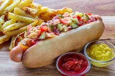 a hot dog with toppings next to some fries