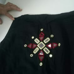 a black shirt with red and white designs on the front is being held by someone's hand