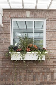 a window box with plants in it on the side of a brick building