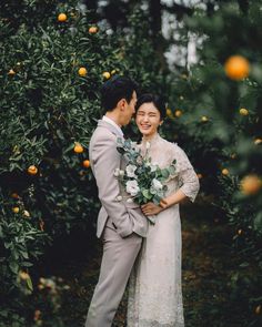 a bride and groom standing in front of an orange tree