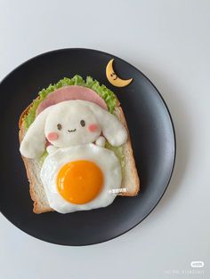 a black plate topped with an egg and bunny sandwich