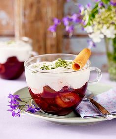 a dessert in a glass bowl on a plate with purple flowers and napkins next to it